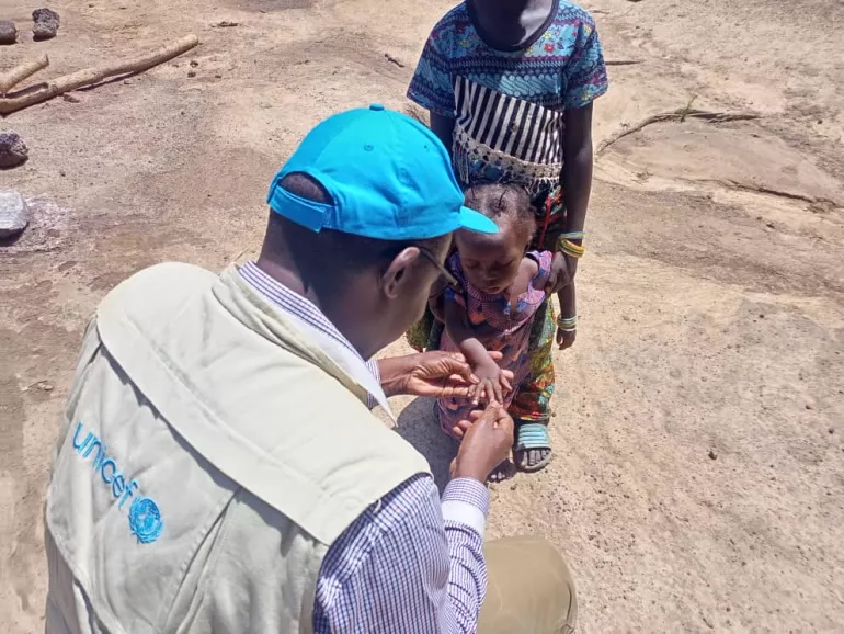 Un personnel de UNICEF qui parle avec un enfant qui vient de se faire vacciner.