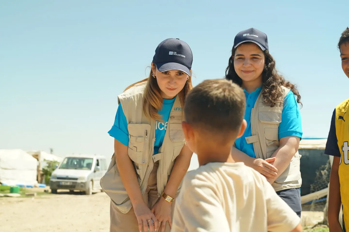 Two UN Volunteers talk to the child 