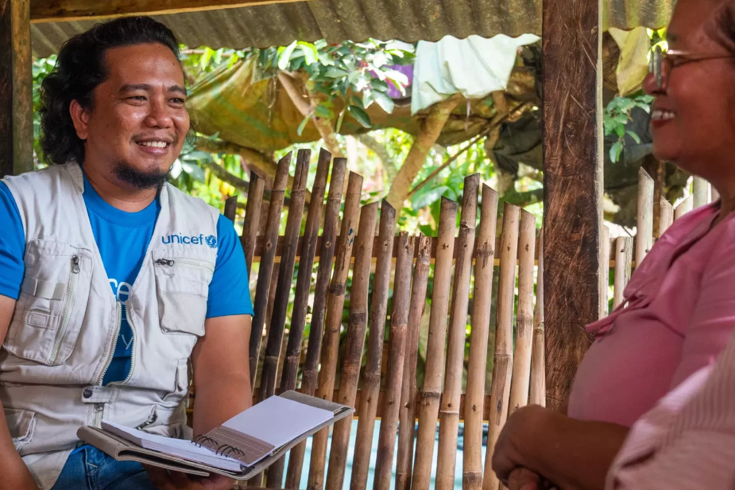Man wearing vest that reads "UNICEF" smiles. Two women sitting next to him smiling. Overlay text reads: "You can always count on volunteers"