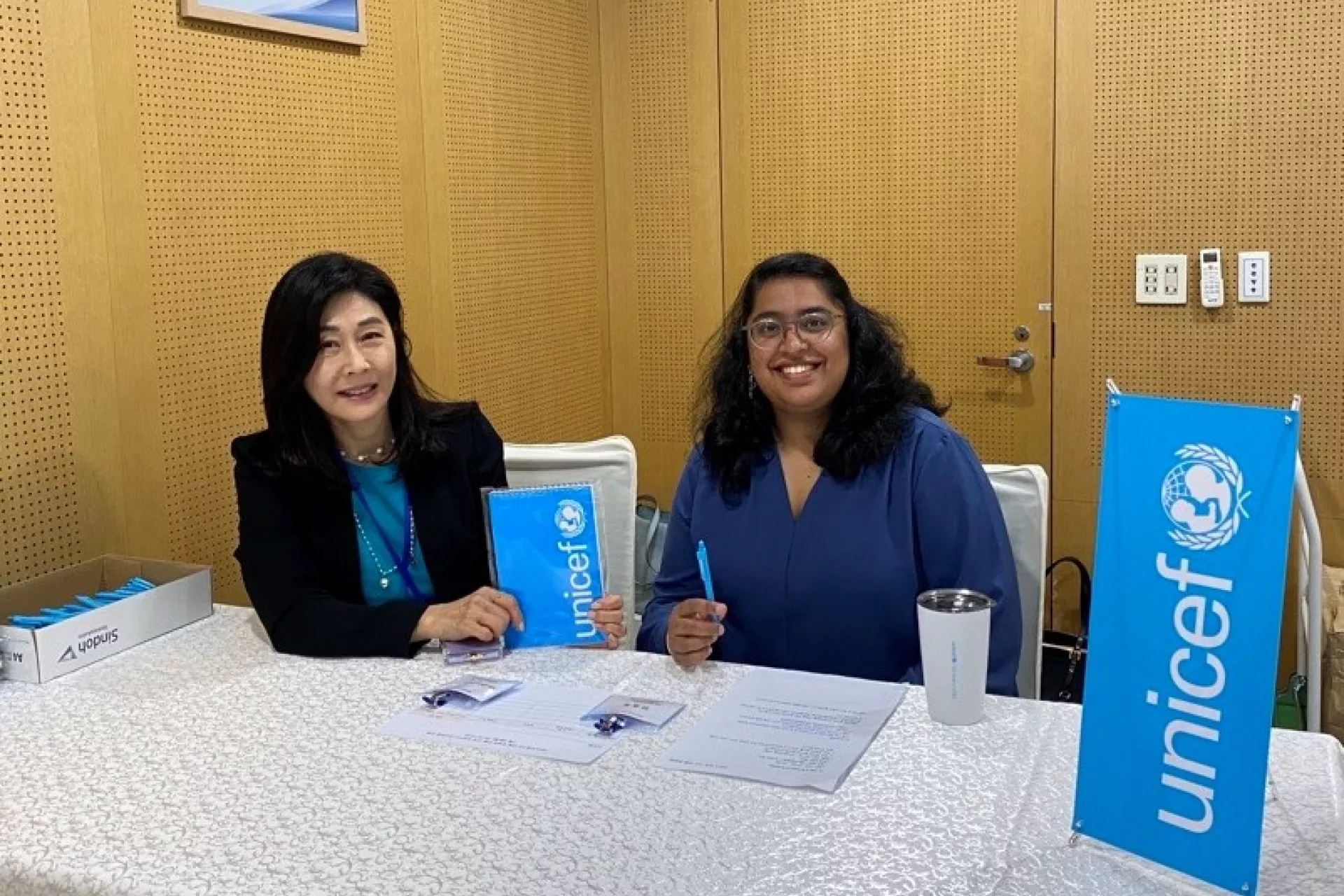 Two women sitting behind a stand and smiling