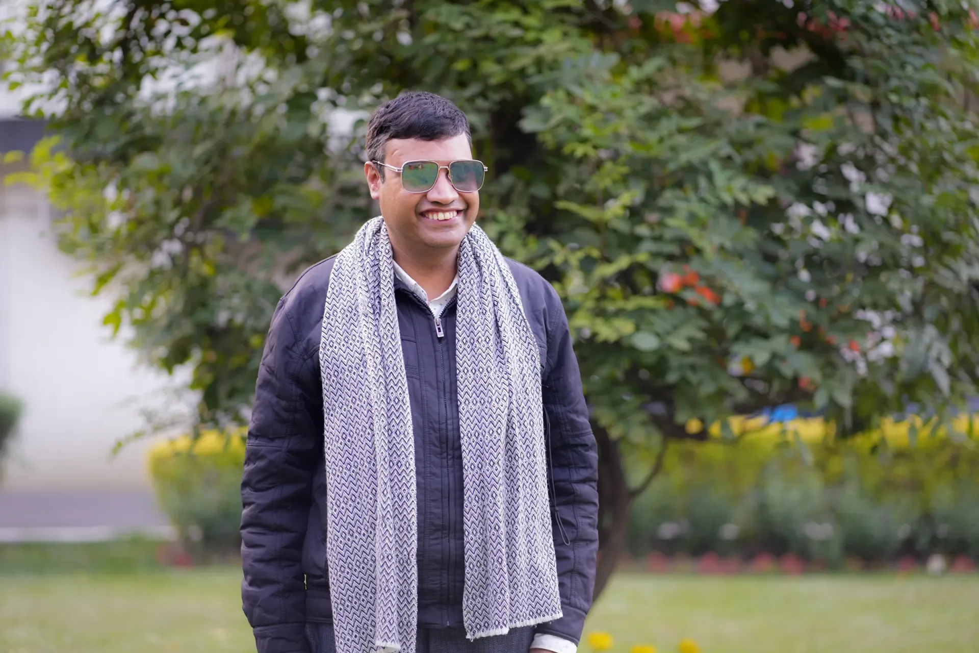 Sushil smiling in the ROSA Gadrden with a tree and a building in the background