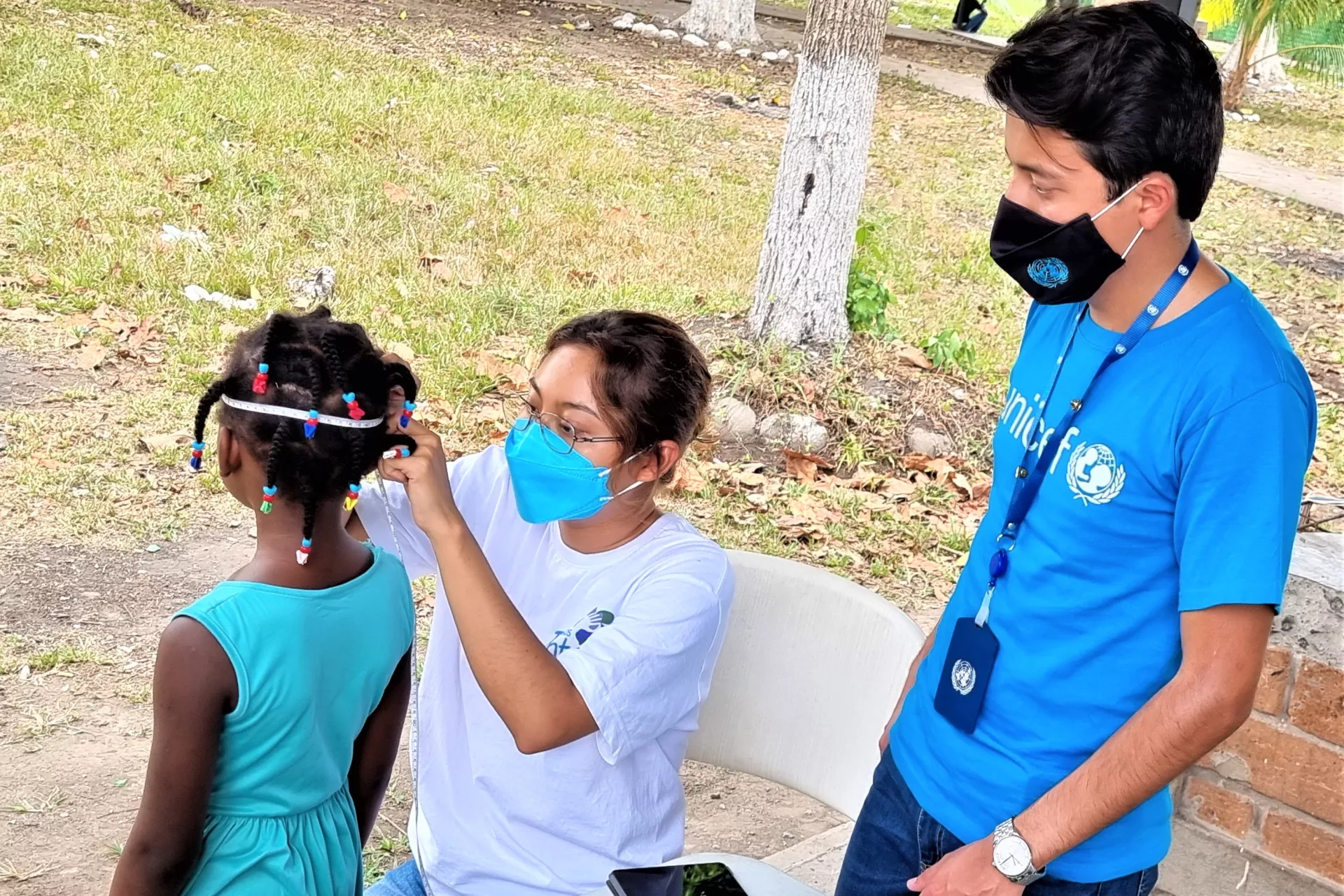 Un joven y una mujer examinan a un ni&ntilde;o migrante