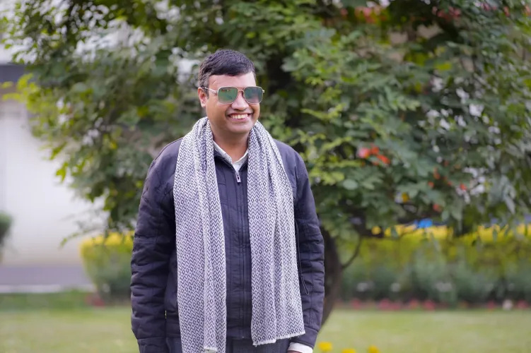 Sushil smiling in the ROSA Gadrden with a tree and a building in the background