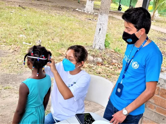 Un joven y una mujer examinan a un ni&ntilde;o migrante
