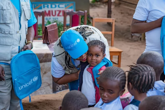 A UNICEFR staff member hugs a little girl