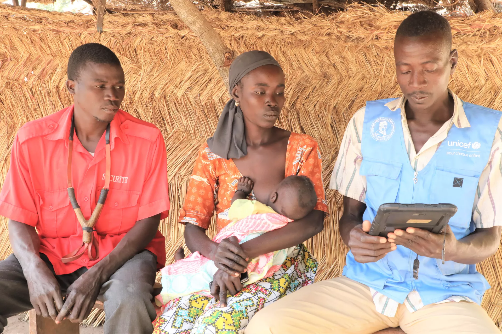 a community health worker sits with a family
