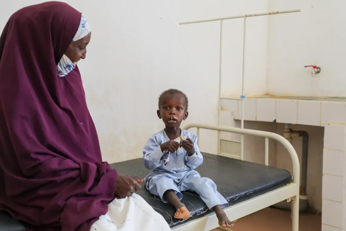 Under his mother's emotional gaze, Mahamat enjoys his first sachet of ready-to-use therapeutic food (RUTF).