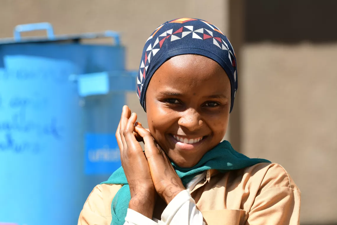 An adolescent girl, smiling in the playground of the school.