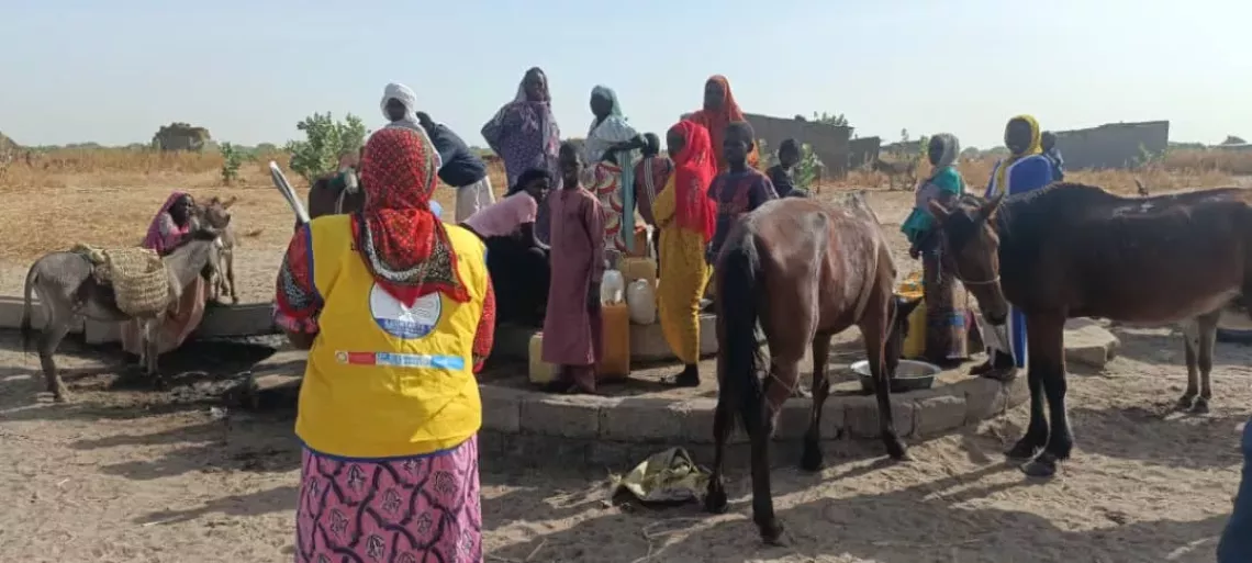 Maimouna raises awareness among a group of people gathered at a village watering hole.