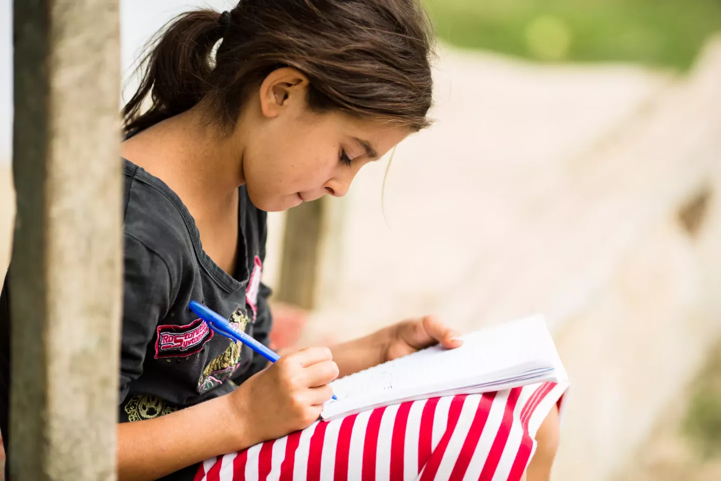 Loredana is doing summer homework on the porch. 