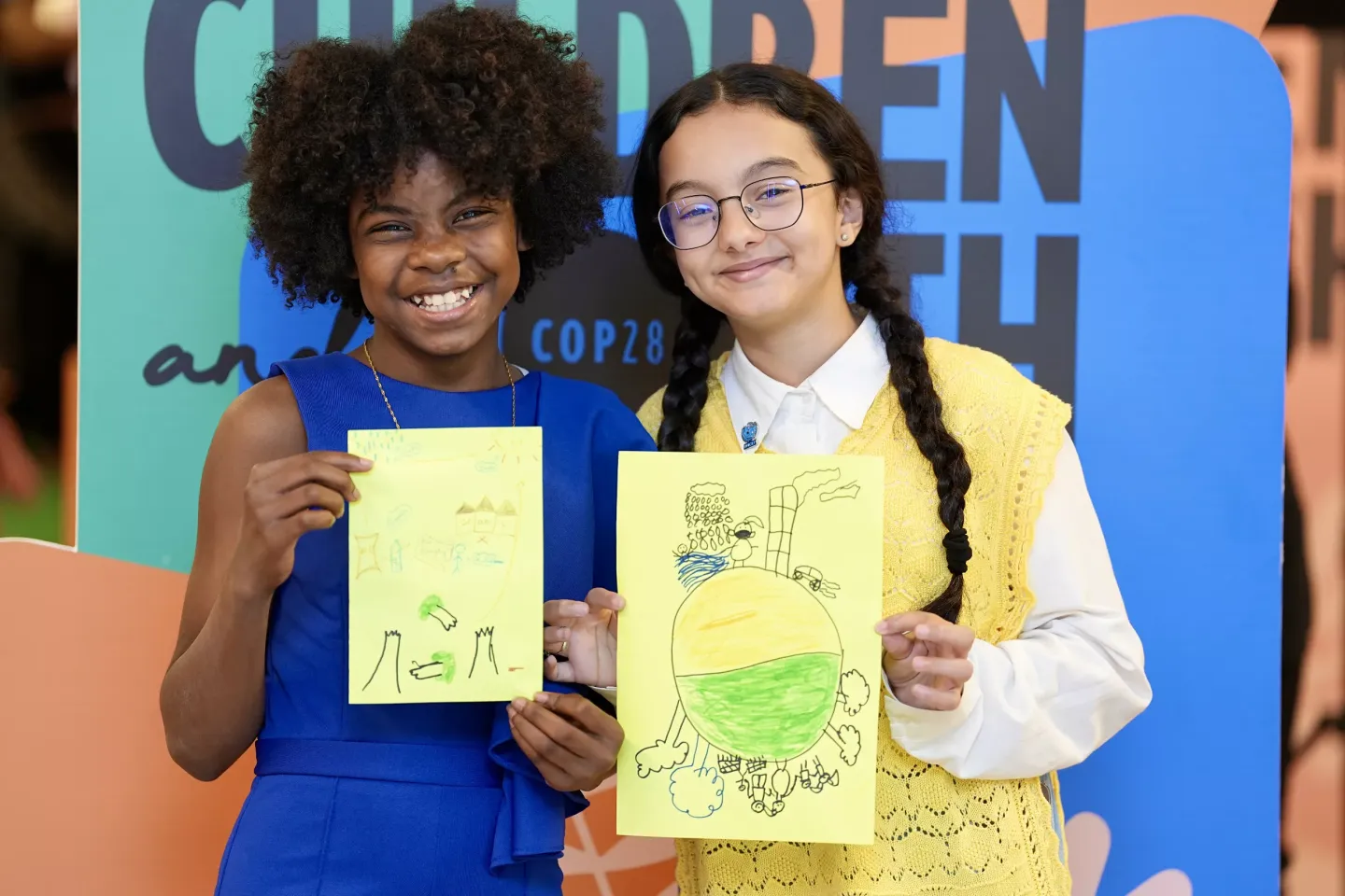 Lova Renee, 13-year-old UNICEF Youth Advocate from Madagascar, and Revan Ahmed, 13-year-old UNICEF Youth Advocate from Libya, pose for a photo with their drawings.