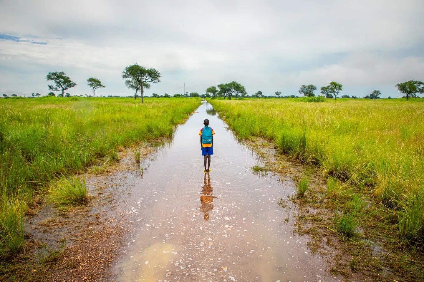 Aboya looks at the flooded road leading to her village