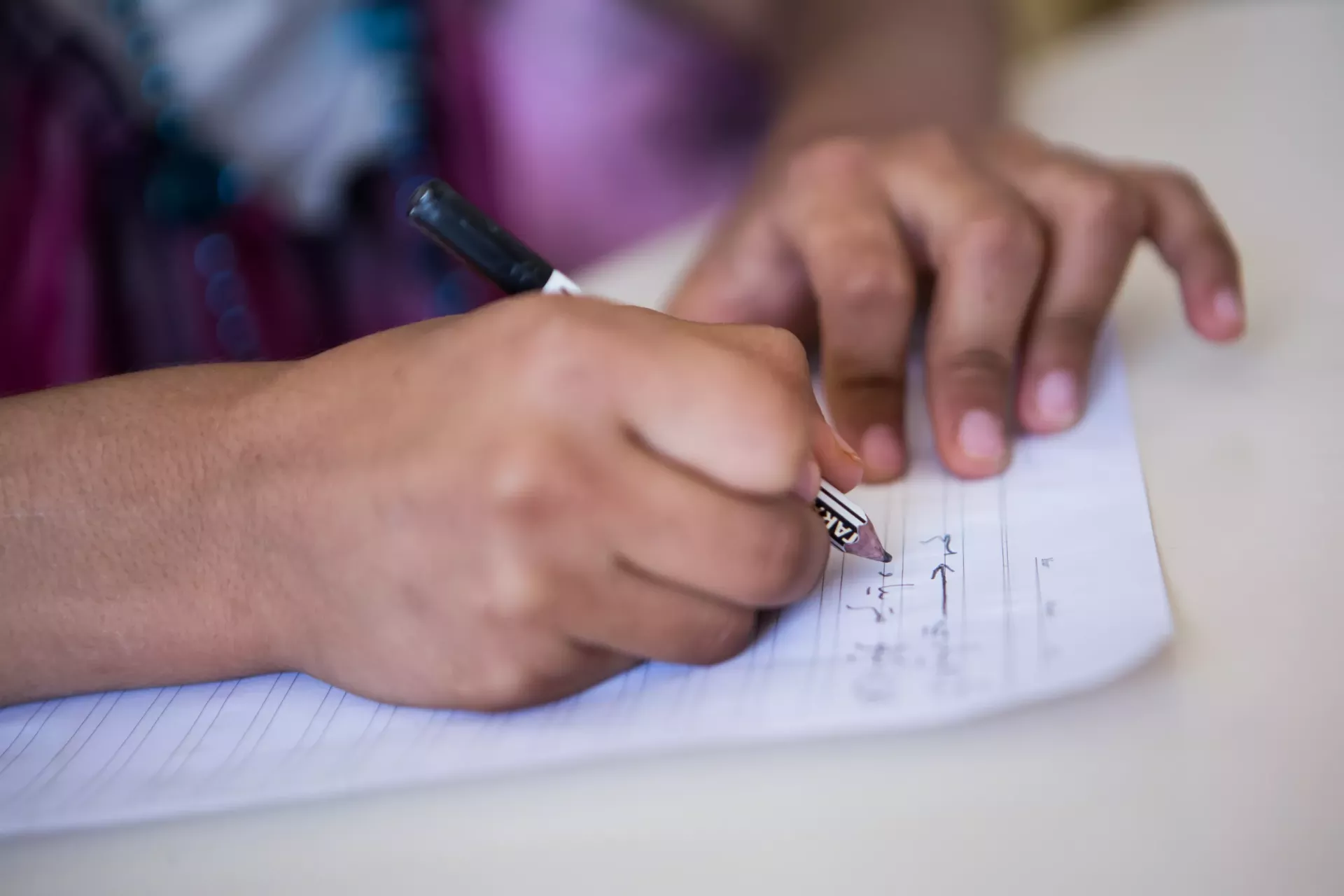 Close up of hands of ten year old Ahin as she is writing during her lesson in the KAR school in the Domiz refugee camp in Northern Iraq.