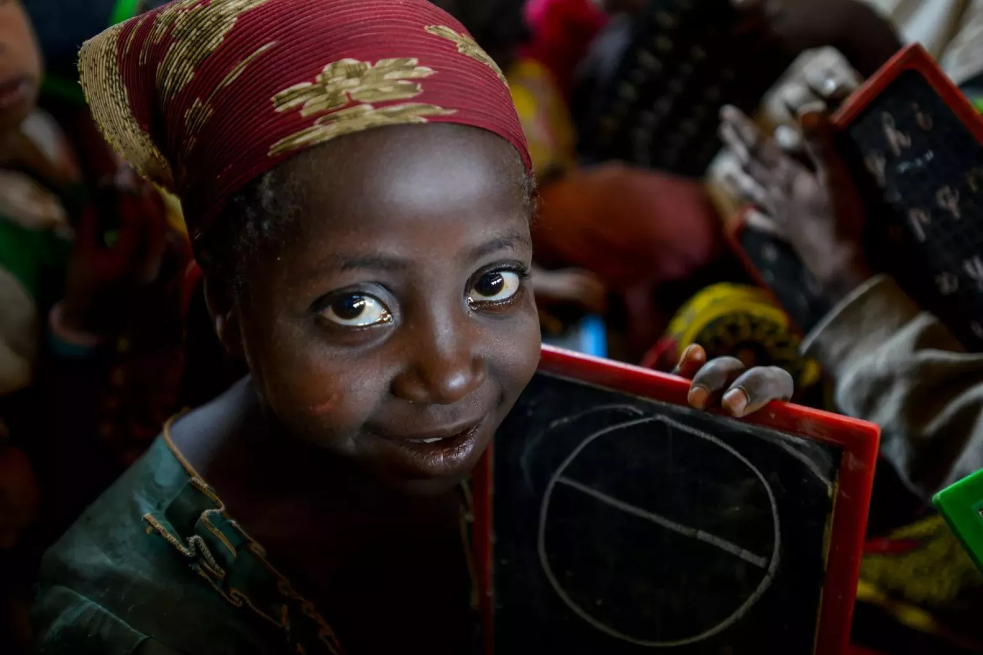 A smiling girl shows the drawing on her slate, in an arts and crafts activity facilitated by the local NGO ASSEJA