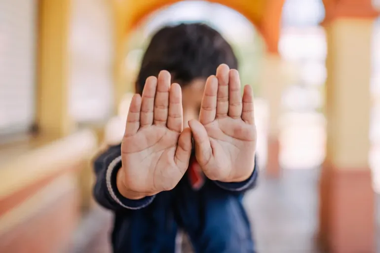 Un ni&ntilde;o con las manos frente a su cara