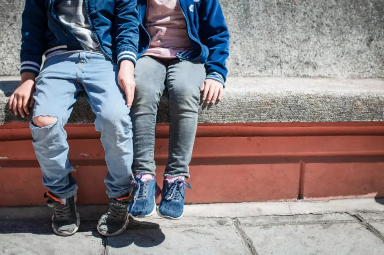 Dos ni&ntilde;os sentados en una banca