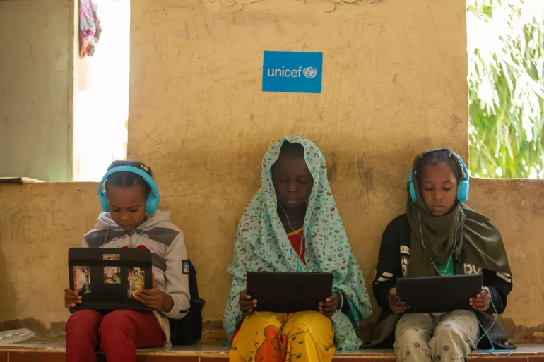 Ni&ntilde;os y ni&ntilde;as desplazados participan en una sesi&oacute;n de aprendizaje digital en el campo para personas desplazadas internamente de Al Salam en el estado de Kassala.