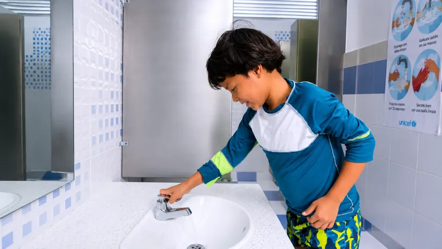 Ni&ntilde;o lav&aacute;ndose las manos en un ba&ntilde;o instalado por UNICEF.