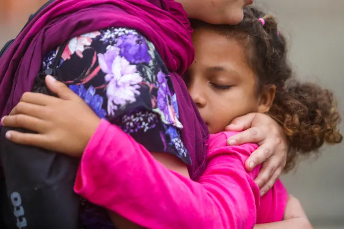 Una ni&ntilde;a se despide de alguien antes de abordar el bus para continuar su trayecto migratorio junto a su familia