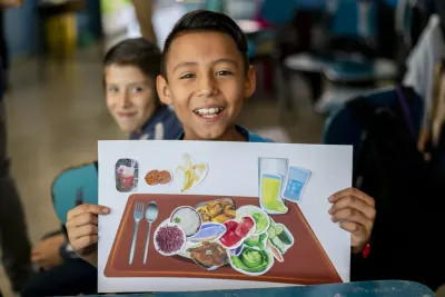 Ni&ntilde;o sonriente con cartel nutrici&oacute;n