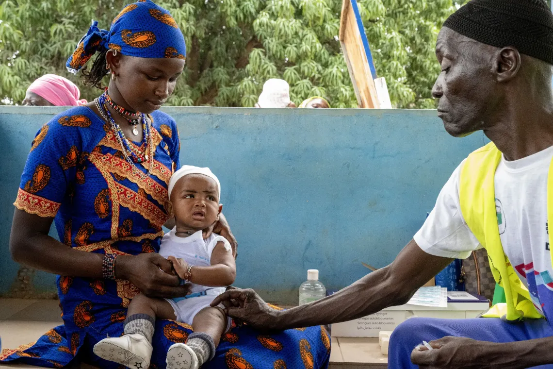 Brahima, agent de sant&eacute; communautaire vaccine un enfant. 