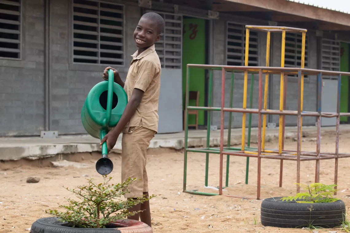 Othniel, 11, watering plants as part of the green schools project.