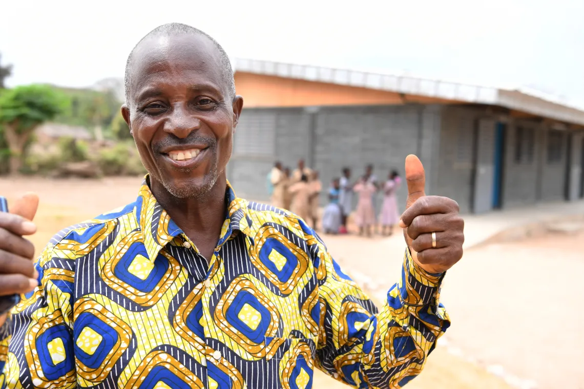 Raymond Konan Yao, President of the development association of Toumoudi-Sakassou is all smiles in front of the plastic bricks school
