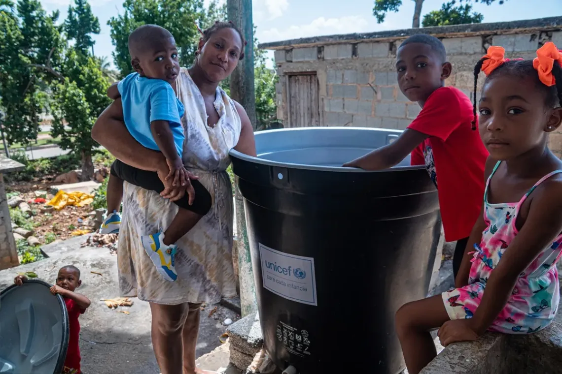Mayda Leydis y sus hijos en el patio de la casa, junto al tanque nuevo donado por UNICEF.