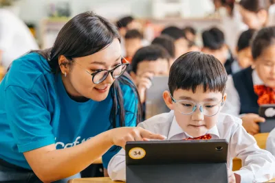 An education officer assisting 4th grader in using digital learning platform