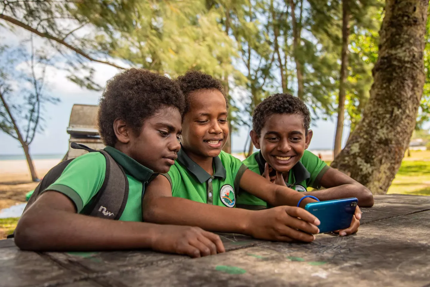 On 29th October, Harry (11yrs) and his friends, Alexino (14yrs) and Shem (10yrs) playing a video game on mobile phone during lunch break, Suango Primary School, Efate in Suango, Port Vila, Vanuatu