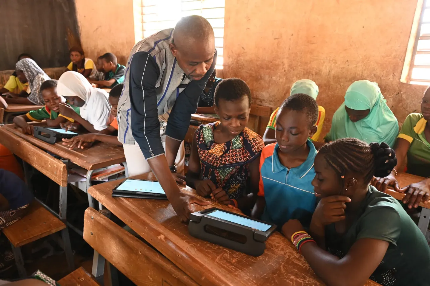 Gansonr&eacute; Amad&eacute; Windemi, a 42 year old teacher, helps children learning with tablets, at their school Kaya, in the northeast of Burkina Faso.