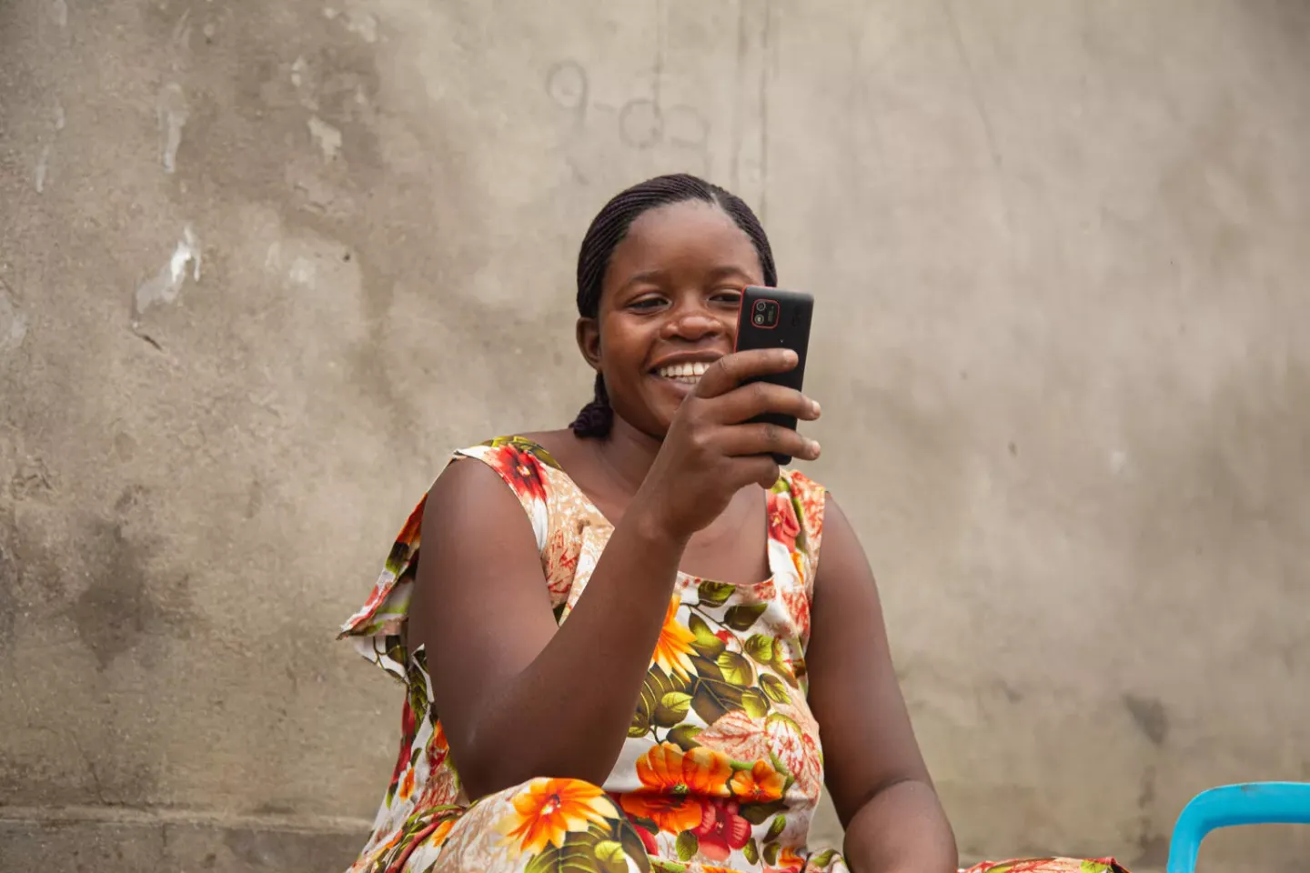 Chance Adisho reads a message on her phone in Goma, North Kivu, DR Congo, on 10 April 2025. Through her phone, she receives support as part of a humanitarian cash transfer programme.