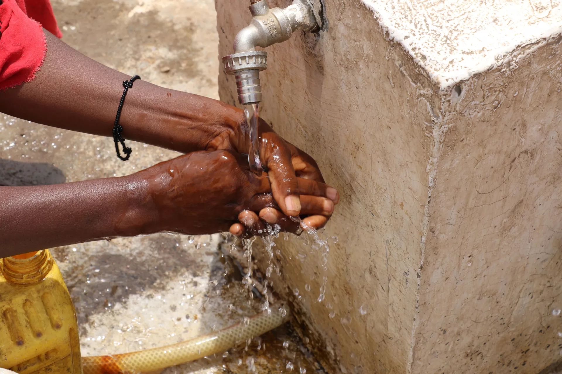A woman fetching water from a water pump