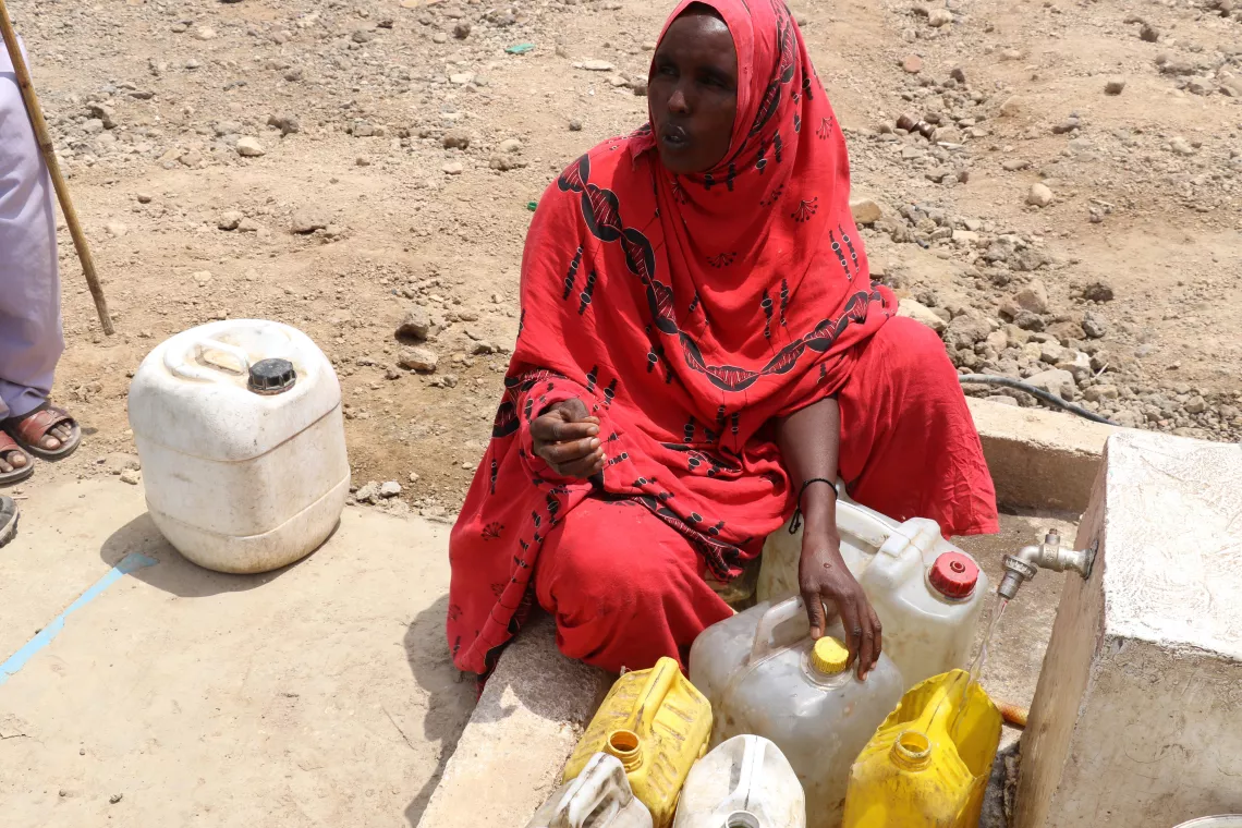 A woman fetching water from a water pump