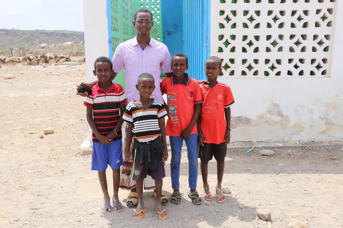 Abdourahman Eltireh  at teacher at Beyadeh Primary School stands with four boys