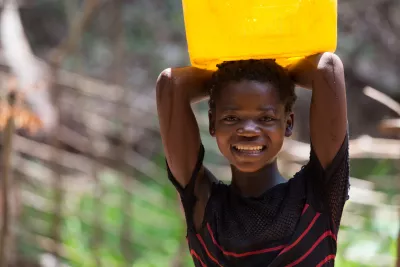 Une jeune fille portant de l'eau sur sa t&ecirc;te.
