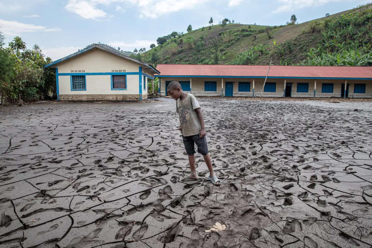 Un enfant regarde le sol recouvert de boue