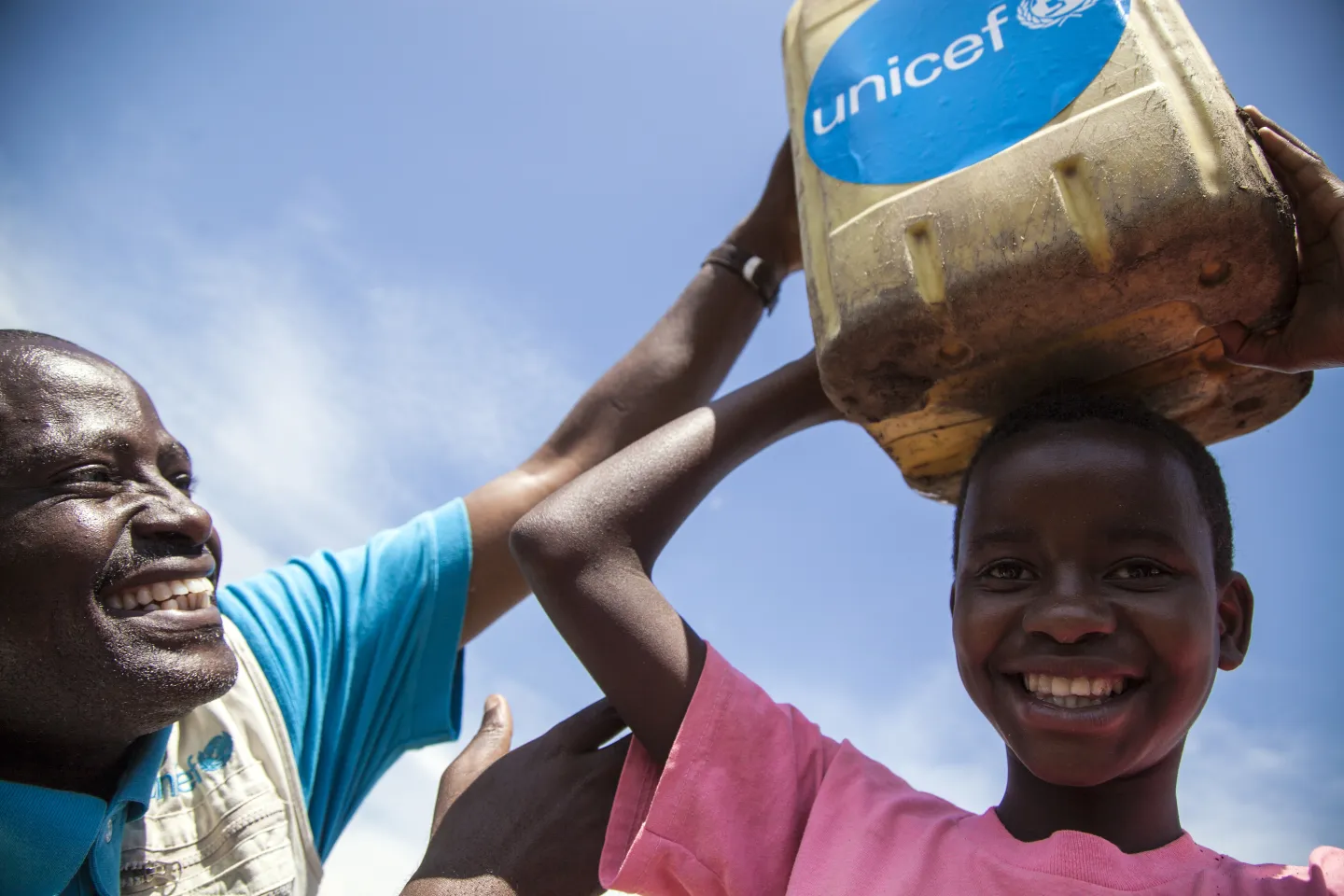Un agent de l'UNICEF aide une fille &agrave; placer l'eau sur sa t&ecirc;te