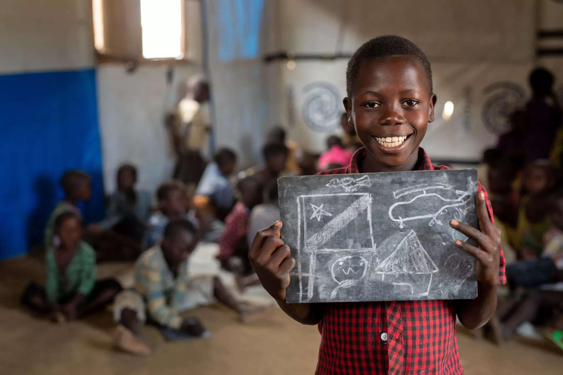 Une fillette tient une ardoise avec des dessins en craie