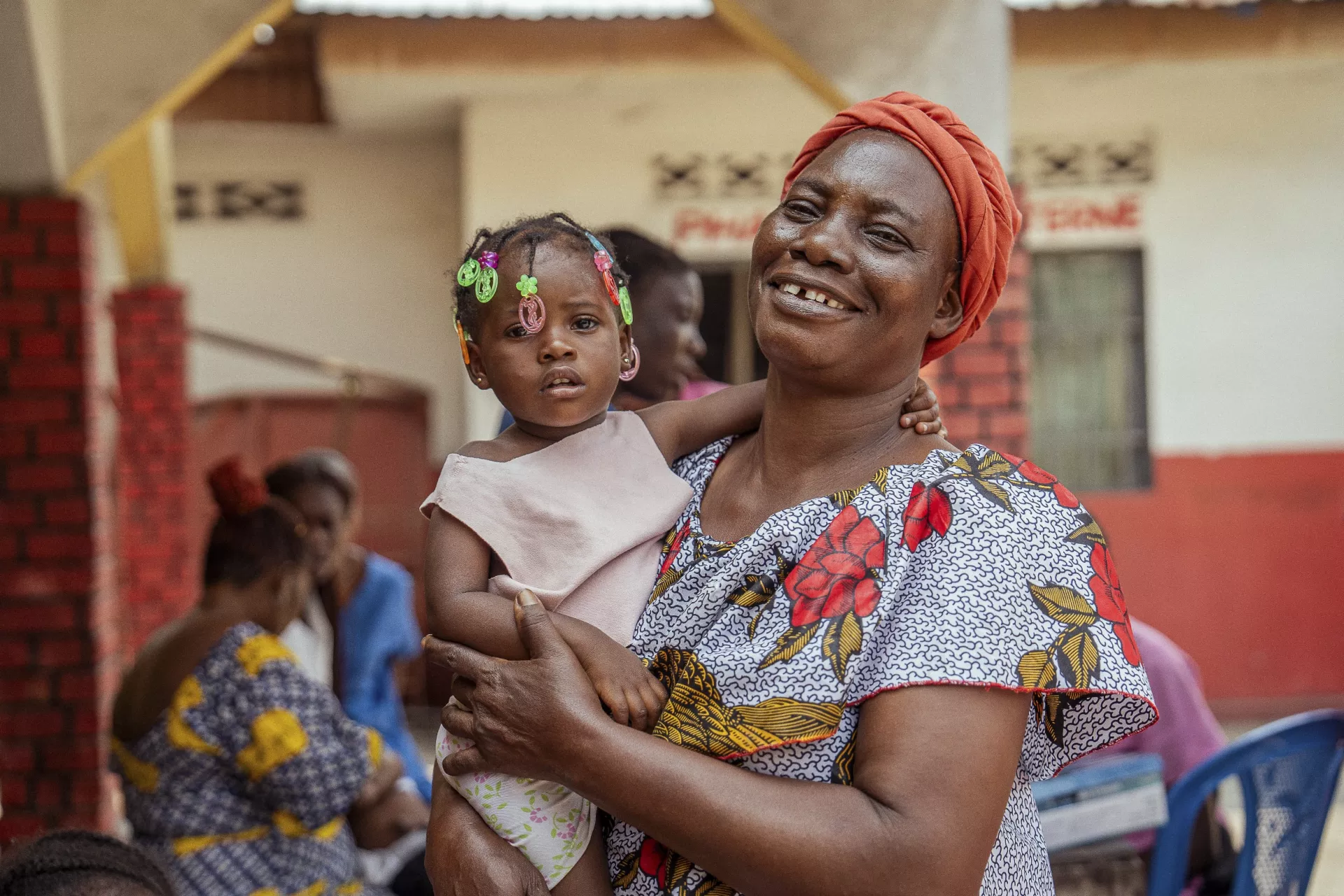 Une femme tenant une petite fille dans ses bras, en affichant un large sourire