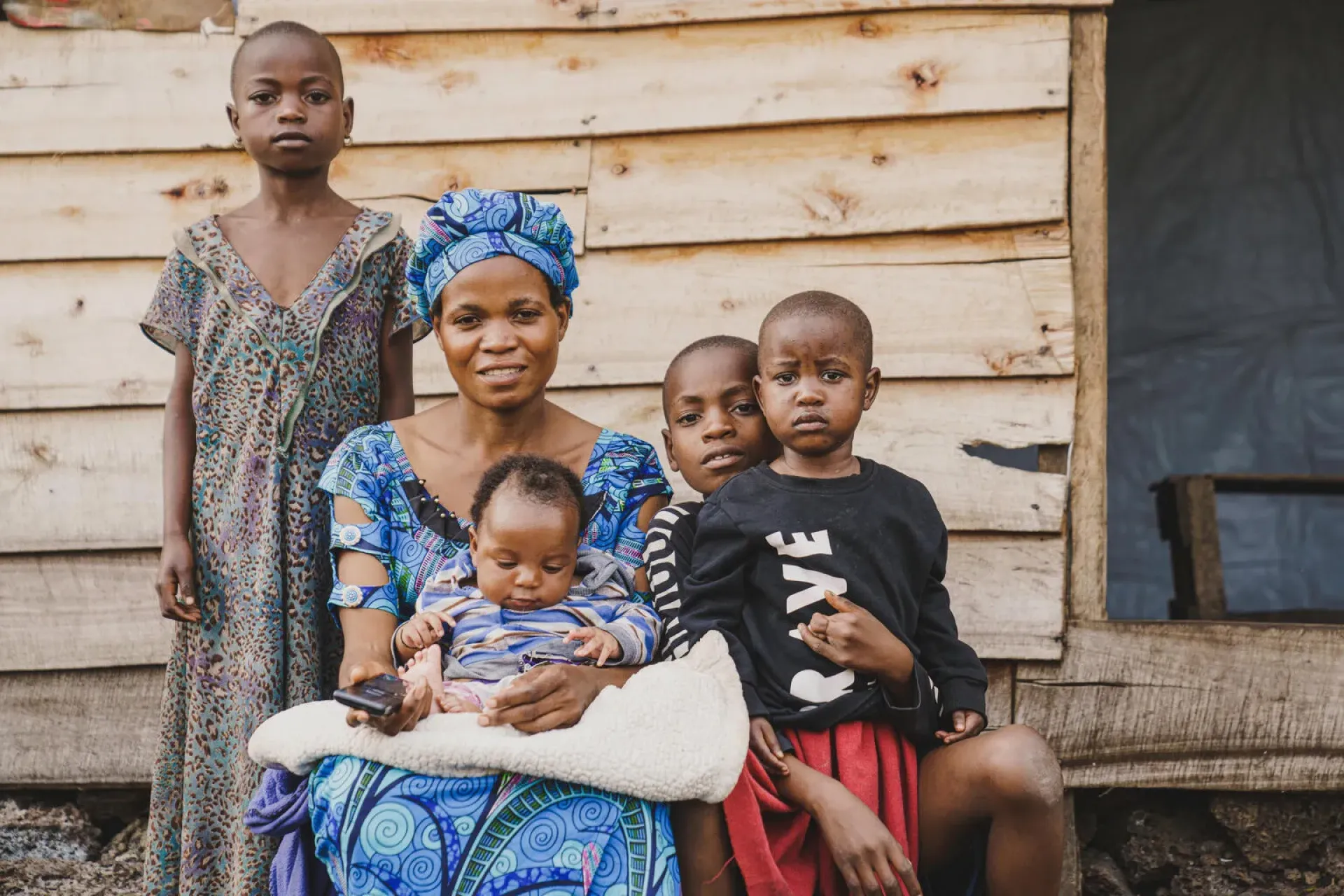 Une femme assise avec un b&eacute;b&eacute; sur les genoux et entour&eacute;e de trois enfants