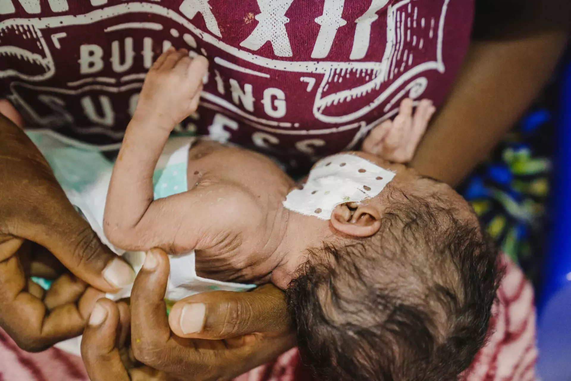 Un enfant avec une oreille band&eacute;e dans les bras d'une femme