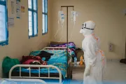 Une professionnelle de sant&eacute; en tenue de protection int&eacute;grale v&eacute;rifie une perfusion dans une salle d'isolement.