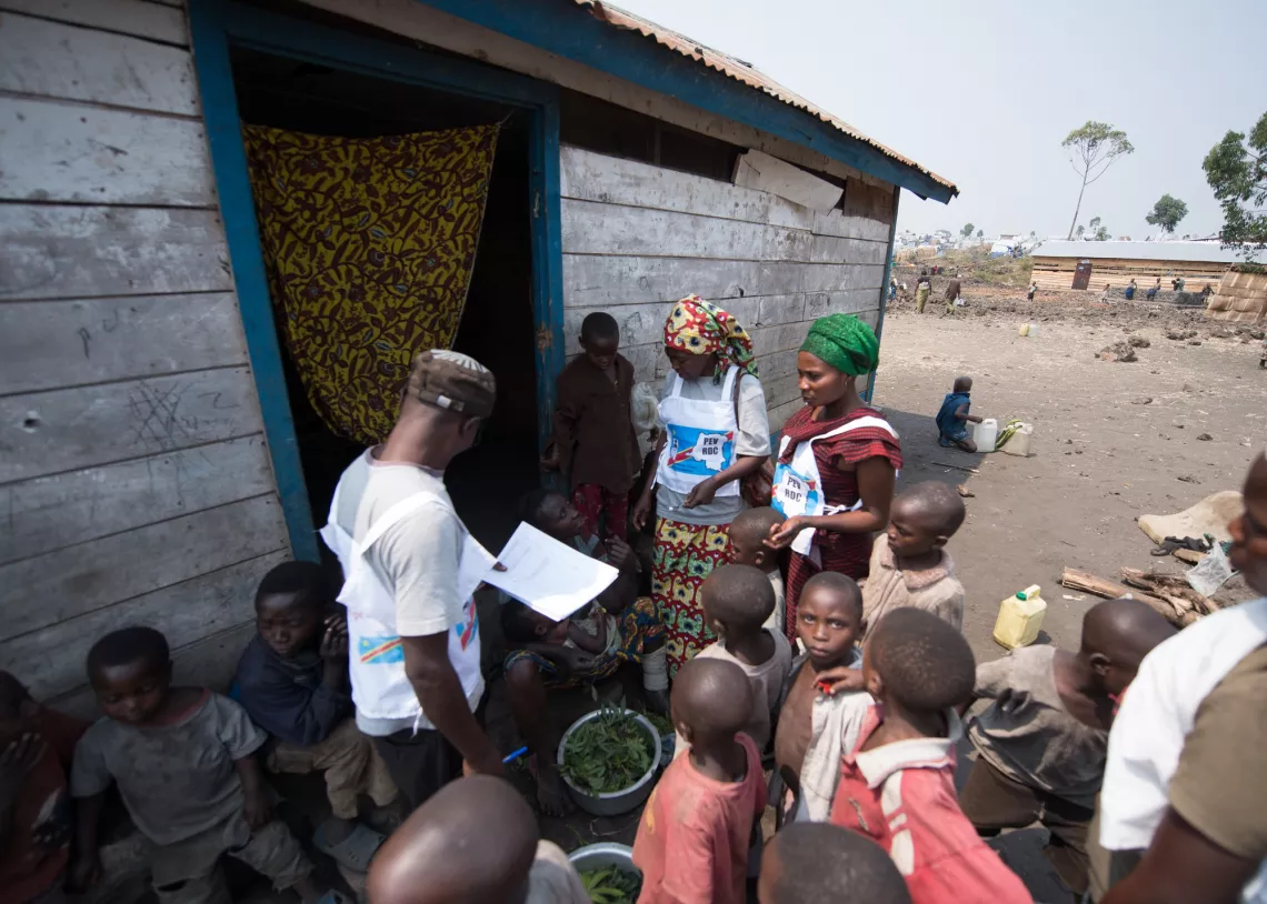 Des vaccinateurs entour&eacute;s d'enfants dans un camp de personnes d&eacute;plac&eacute;es