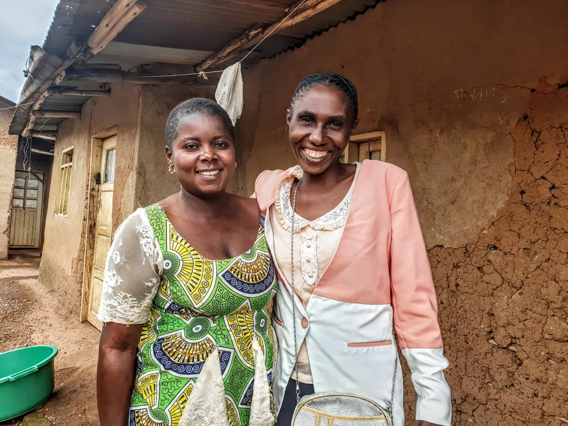 Deux femmes souriantes se tenant devant une maison 