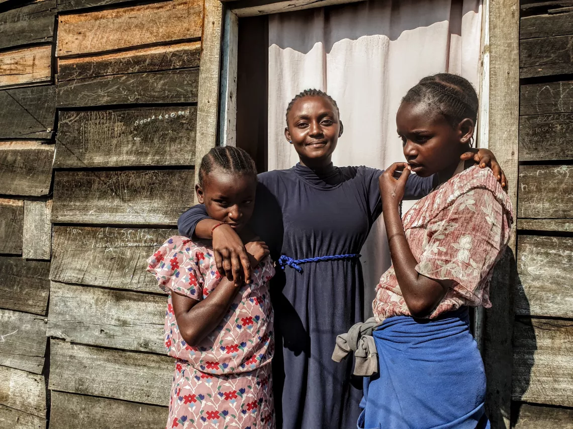 Trois soeurs qui sourient devant la porte de leur maison