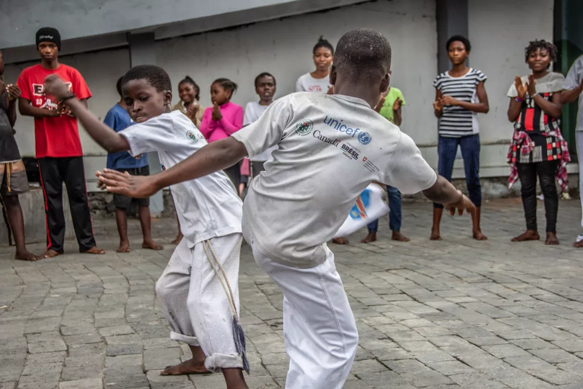 Deux enfants qui pratiquent la capoeira au milieu d'une foule de jeunes