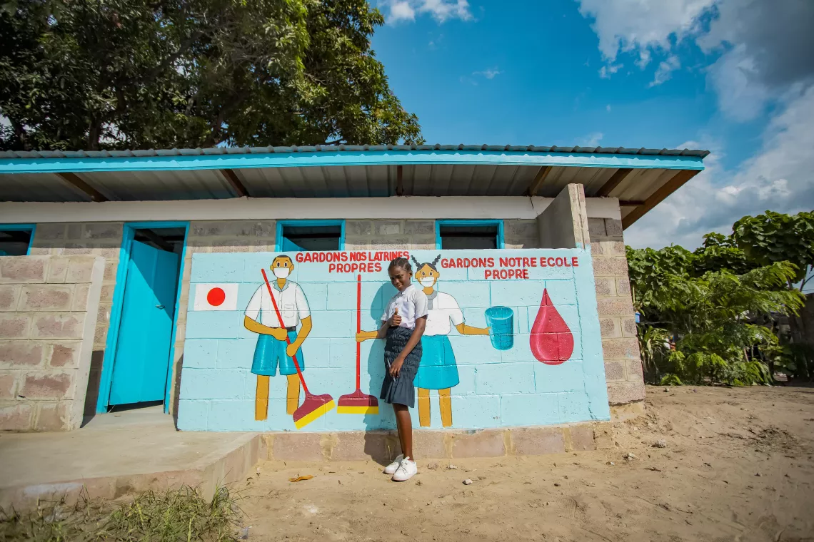 Katangi pose devant les nouvelles installations sanitaires de son &eacute;cole.