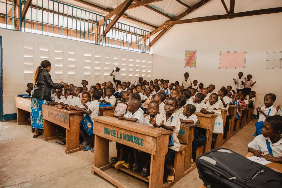 Une salle de classe avec des enfants assis sur des pupitres en bois
