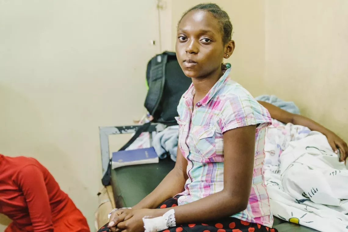 Un fille avec un bandage sur l'avant bras est assise sur un lit d'h&ocirc;pital